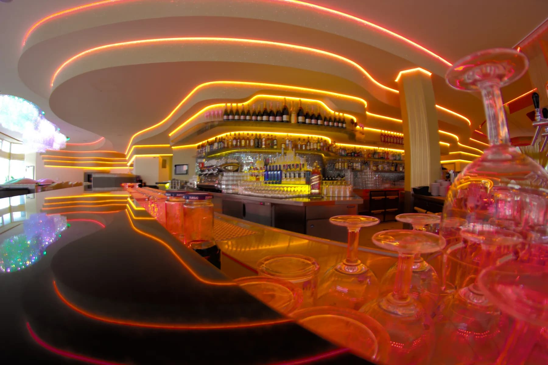 MIO Berlin bar at night with glowing counter and glasses in the foreground