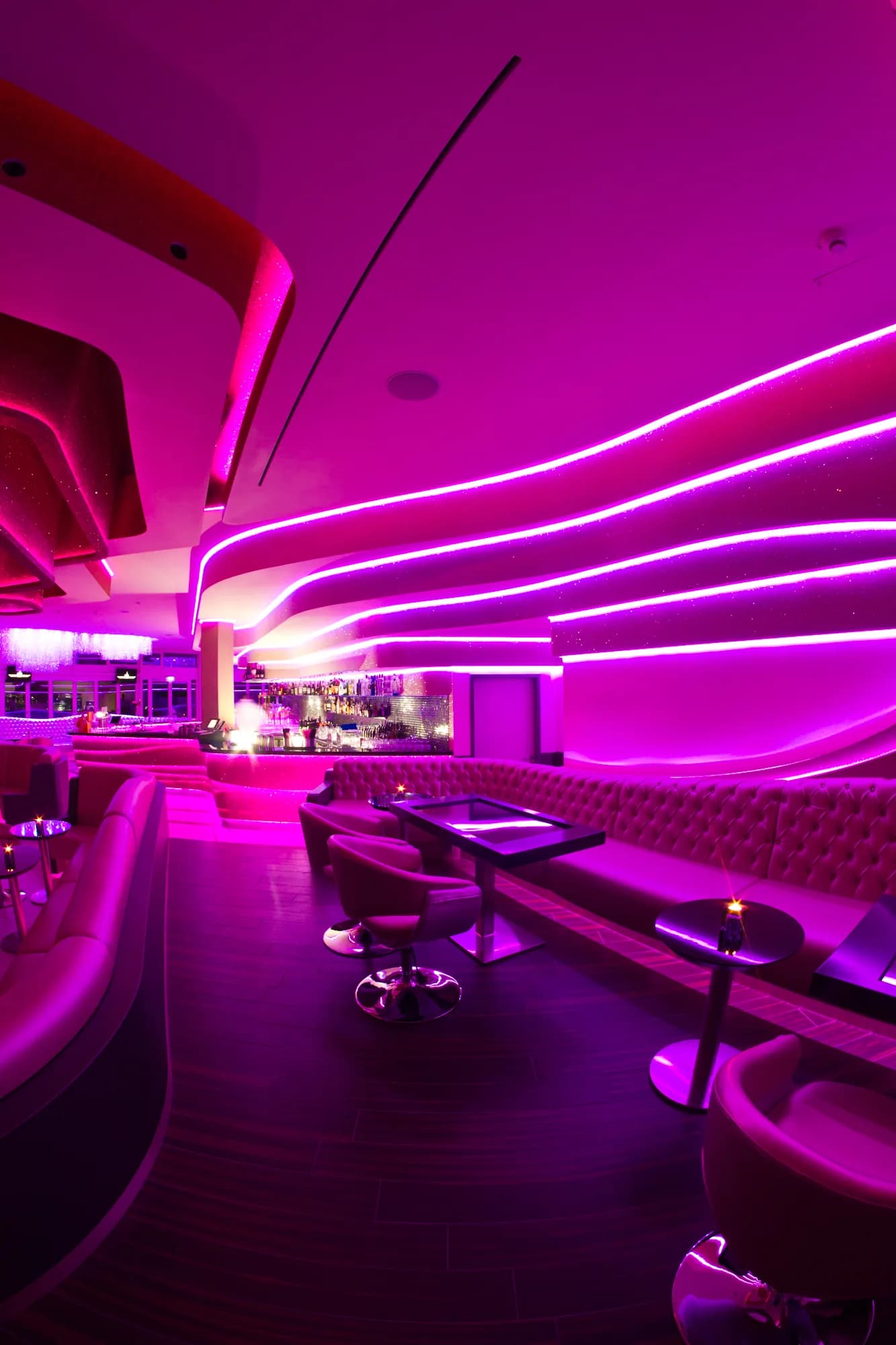 MIO Berlin lounge in magenta light with curved LED lines on the ceiling